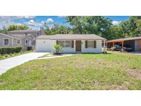 Charming single-story home with a well-maintained lawn, refreshed white paint, and a cozy carport at 118 Deacon Jones Blvd, Orlando, FL 32810