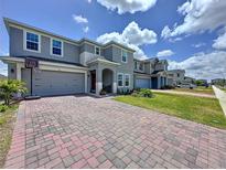 Two-story home with a brick paver driveway, landscaping and a two-car garage at 1181 Lone Palm Way, St Cloud, FL 34771