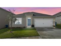 Charming single-story home featuring a manicured lawn, attached garage, and inviting blue front door, perfect for first-time homebuyers at 1828 Buckeye Rd, Davenport, FL 33837