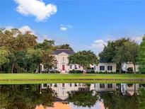 Beautiful home on a pond with lush landscaping, a red front door, and reflective sunset views at 202 Acadia Ter, Kissimmee, FL 34747