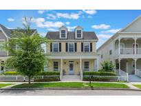 Charming two-story yellow home with a welcoming front porch and white picket fence at 206 Norfolk Pl, Celebration, FL 34747