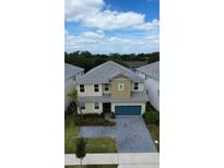 Charming two-story home features a paver driveway, manicured lawn, and a blue two-car garage at 2386 Rama Dr, Kissimmee, FL 34746
