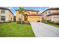 Inviting two-story home with a well-manicured lawn, palm tree, and a two-car garage and red tile roof at 2630 Tranquility Way, Kissimmee, FL 34746