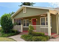 Charming bungalow featuring a cozy front porch with a red door and meticulously landscaped yard at 2810 Elizabeth Ave, Orlando, FL 32804