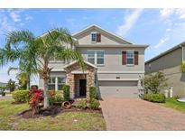 Two-story home featuring a manicured lawn, lovely stone accents, and a brick driveway at 2901 Harvest Hill Ln, Orlando, FL 32824