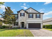 Beautiful two-story home featuring a stone facade, lush lawn and attached two car garage at 3425 Middlebrook Pl, Harmony, FL 34773