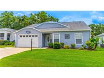 Charming single-story home featuring a well-maintained lawn and a white garage door at 5426 Astor St, Leesburg, FL 34748