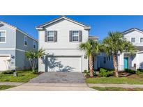 Charming two-story home featuring a well-maintained lawn and a two-car garage at 7184 Oakmoss Loop, Davenport, FL 33837