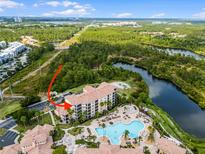 Stunning aerial view of condo community featuring pool, lake, and lush landscaping at 8601 Worldquest Blvd # B1/U3502, Orlando, FL 32821
