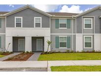 Charming townhome featuring a manicured lawn, symmetrical landscaping, and a stylish gray and white facade at 971 Paradise Dr, Davenport, FL 33897