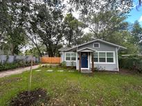 Charming gray home features a blue front door and a neatly landscaped yard with mature trees at 1407 Noble Pl, Orlando, FL 32801