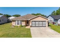 Charming single-story home featuring a well-maintained lawn, neutral paint, and attached two car garage at 1543 Reade Cir, St Cloud, FL 34772