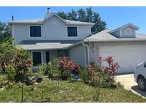Charming two-story home with an attached garage and a welcoming front yard filled with plants at 172 Pinewood Cir, Kissimmee, FL 34743