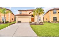 Inviting two-story home featuring a terra cotta roof, two-car garage and mature palm trees at 2628 Tranquility Way, Kissimmee, FL 34746