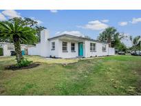Charming, renovated one-story home featuring a bright turquoise front door, lush landscaping, and a crisp white exterior at 4420 Lake Lawne Ave, Orlando, FL 32808