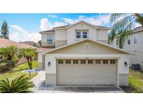 A two-story home boasts a two-car garage, a well-manicured lawn, and stylish exterior lighting at 521 Rena Dr, Davenport, FL 33897