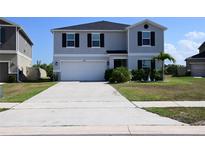 Two-story home showcasing a spacious driveway, two-car garage, manicured lawn, and charming landscaping details at 673 Sarner Pass Way, Winter Haven, FL 33881
