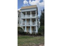 Three story condo building with white balconies and trim over a yellow base near mature landscaping at 7509 Mourning Dove Cir # 303, Reunion, FL 34747