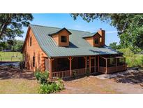 Charming log cabin featuring a metal roof, dormer windows, and a screened-in porch, perfect for relaxing outdoors at 1850 Orangewood Ave, St Cloud, FL 34772