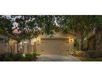 A single-Gathering home featuring an attached two-car garage and a stone-paved driveway, with lovely trees providing shade at 2376 Palm Tree Dr, Kissimmee, FL 34759