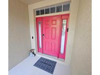 Bright pink front door with sidelights and transom window, features a 'welcome' mat and charming decor at 2531 Old Kent Cir, Kissimmee, FL 34758