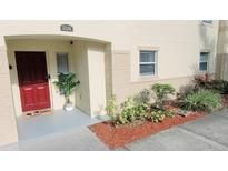 Charming townhouse entrance with red door and freshly landscaped garden at 2729 Club Cortile Cir, Kissimmee, FL 34746