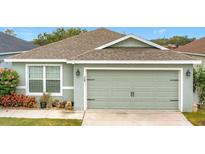 Charming home featuring a well-maintained lawn, a two-car garage, and light green paint at 369 St Georges Cir, Eagle Lake, FL 33839