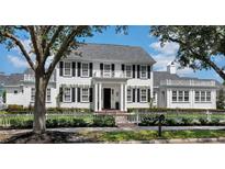 Charming two-story home features a white picket fence, black shutters, and a well-manicured lawn at 423 Arbor Cir, Celebration, FL 34747