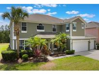 Inviting two-story home with a three-car garage, lush tropical landscaping, and a well-manicured lawn at 8571 La Isla Dr, Kissimmee, FL 34747