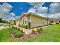 Charming home features a stone facade, tiled roof, manicured lawn, and beautiful landscaping at 1082 Blackwolf Run Rd, Davenport, FL 33896