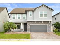 Charming two-story home featuring a stone facade, gray paint, and well-manicured landscaping at 14160 Dove Hollow Dr, Orlando, FL 32824