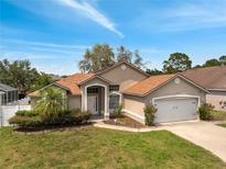 Charming single-story home featuring a well-manicured lawn and an attached two-car garage at 149 Imperial Oak Ct, Davenport, FL 33896