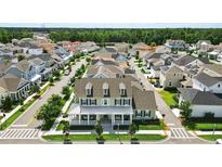 Expansive aerial view of a neighborhood with a meticulously landscaped two-story home at the forefront at 1850 Treasure Cv, Celebration, FL 34747