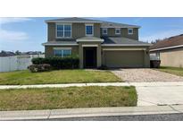 Two-story home with a two car garage, manicured front yard and brick driveway at 4714 Greycliff Prairie Dr, Kissimmee, FL 34758