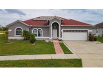 Charming single Gathering home featuring a well-manicured lawn and solar panels on a red roof at 5418 Crepe Myrtle Cir, Kissimmee, FL 34758