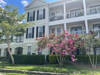 A charming multi-story condo featuring dual balconies, black shutters, lush landscaping, and beautiful flowering crepe myrtles at 239 Longview Ave # 107, Celebration, FL 34747