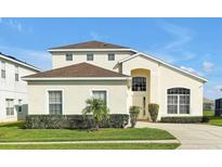 Charming two-story home featuring a well-manicured lawn and arched entryway at 553 Bailey Cir, Davenport, FL 33897