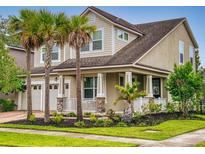 Charming two-story home with palm trees and a covered porch with stone accents and a two car garage at 8635 Tallfield Ave, Orlando, FL 32832