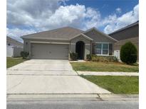 Charming single-story home featuring a well-maintained lawn and a two-car garage on a sunny day at 1895 Hickory Bluff Rd, Kissimmee, FL 34744