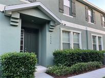 Charming townhome exterior with a covered entry, green paint, and well-maintained landscaping at 10734 Dawson Lily Way # S, Orlando, FL 32832