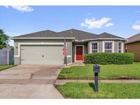 Charming single-story home with a two-car garage and well-maintained landscaping and red front door at 2060 Patriot Way, St Cloud, FL 34769