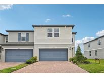 Inviting two-story townhome featuring a blue-gray garage door and manicured front yard landscaping at 2462 Sweet Viburnum Way, Ocoee, FL 34761