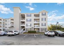 Three-story condo building featuring balconies, neutral siding, and a well-maintained parking area under a blue sky at 3175 Feltrim Pl # 101, Kissimmee, FL 34747