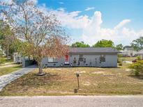 Charming single-story home with grey paint, red front door and well-maintained lawn at 320 S Seminole Ave, Lake Alfred, FL 33850