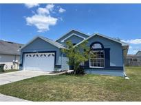 Charming blue single-story home featuring a well-maintained lawn, two car garage, and manicured landscaping at 664 Eagle Pointe S, Kissimmee, FL 34746