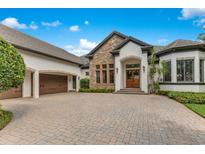 Beautiful home with stone accents, a brick driveway, and a three-car garage at 6761 Valhalla Way, Windermere, FL 34786