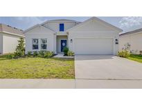 Charming single-Gathering home featuring a well-manicured lawn, blue door, and attached two-car garage at 824 Ofanto Way, Haines City, FL 33844