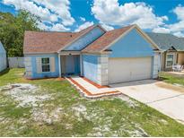 Charming one-story blue home with a two-car garage and manicured front yard at 8322 Cascade Oaks Dr, Orlando, FL 32822