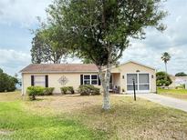 Charming home featuring a beige exterior, well-maintained landscaping, and a convenient attached garage at 1410 Sanchez Ct, Lady Lake, FL 32159