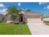 Charming single-story home with a stone facade, well-maintained lawn, and a two-car garage on a sunny day at 1746 Golfview Dr, Kissimmee, FL 34746